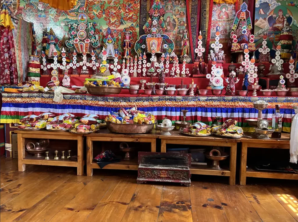 Vibrantly decorated altar in a Himalayan monastery with bowls, ritual items, and colorful fabric hangings.