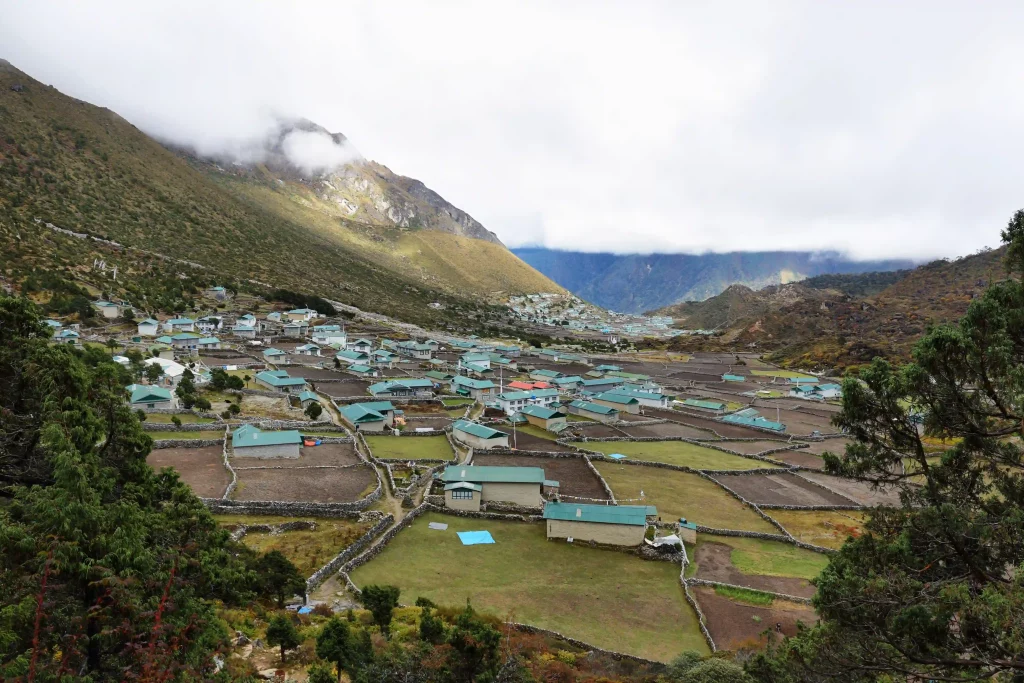 Traditional stone houses in Khumjung village with locals walking peacefully along narrow paths, set against the backdrop of the Himalayas — a cultural highlight of the Everest View Trek, featuring the historic Hillary School and authentic Sherpa life.